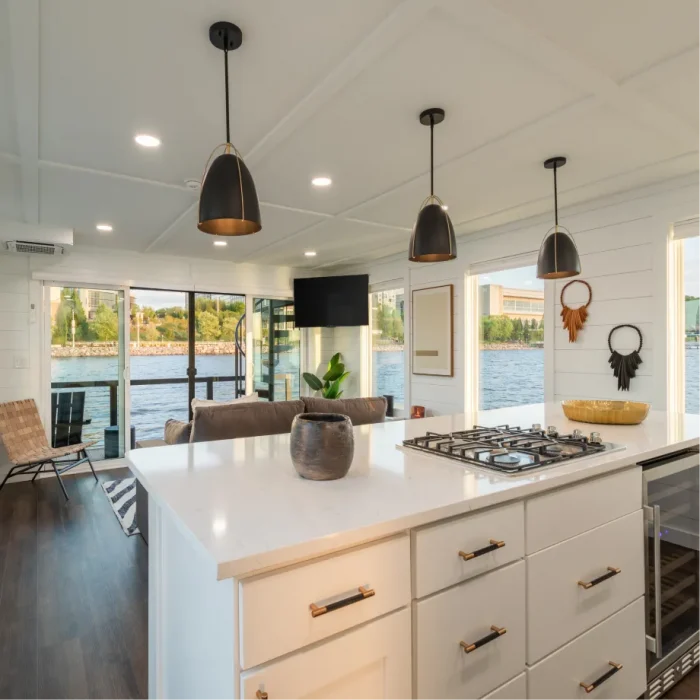 A bright houseboat interior with a long quartz counter and wide windows onto the water.