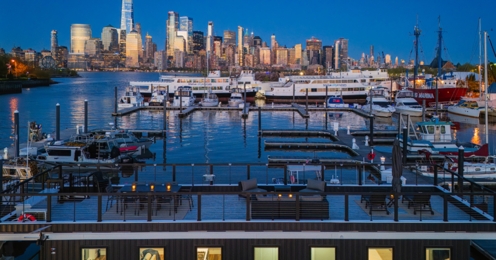 FLOHOM 16 Isaac's Way rooftop deck at Liberty Landing Marina with Lower Manhattan skyline and One World Trade across the Hudson