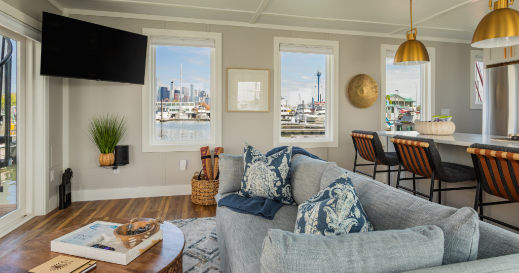 FLOHOM 16 Isaac's Way interior living and kitchen with brass pendants and windows framing the Manhattan skyline across the Hudson