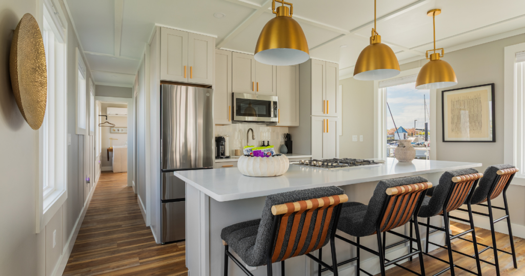 FLOHOM 16 Isaac's Way kitchen with three brass dome pendants over quartz island gas range and leather-strap counter stools
