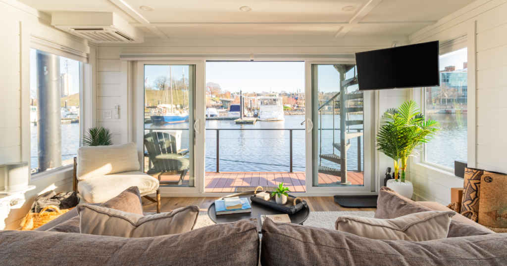 FLOHOM 1 Bay Escape interior living room with sliding glass doors opening to Baltimore Inner Harbor Marina and spiral staircase